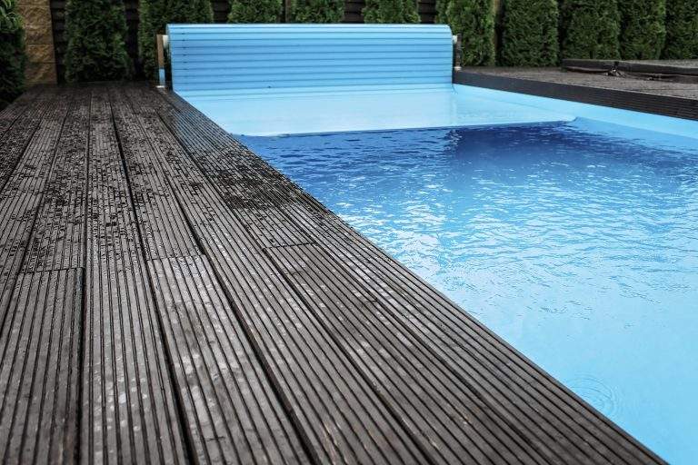 Automatic swimming pool covering system, safely protect children and pets from accidental contact with water, home and cottage equipment, copyspace, place for text, outdoor exterior